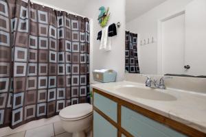 a bathroom with a sink and a toilet and a shower curtain at Chic Townhouse Steps to the Beach Outdoor Pools in Panama City Beach