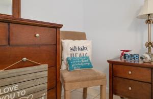 a bedroom with a dresser and a chair with a pillow at Chic Townhouse Steps to the Beach Outdoor Pools in Panama City Beach