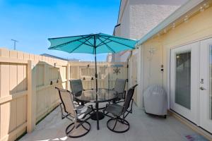 a table with chairs and an umbrella on a patio at Chic Townhouse Steps to the Beach Outdoor Pools in Panama City Beach
