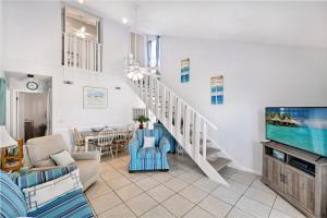 a living room with a staircase and a tv at Chic Townhouse Steps to the Beach Outdoor Pools in Panama City Beach