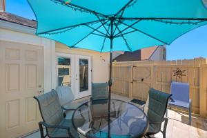 a glass table with chairs and a blue umbrella at Chic Townhouse Steps to the Beach Outdoor Pools in Panama City Beach
