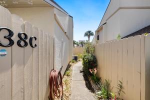 a fence next to a sidewalk next to a building at Chic Townhouse Steps to the Beach Outdoor Pools in Panama City Beach