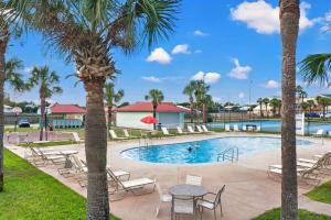 a pool with tables and chairs and palm trees at Chic Townhouse Steps to the Beach Outdoor Pools in Panama City Beach
