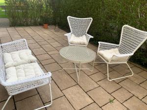 3 Korbstühle und ein Tisch auf einer Terrasse in der Unterkunft RELAX Apartment mit Garten - Lifestyle am Bodensee, Fahrräder inklusive in Bregenz