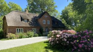 a large brick house with flowers in front of it at Reetdachhaus Warft Simmerdeis - Maisonettewohnung in Oldenswort