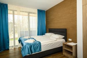 a bedroom with a bed with blue curtains and a window at Хотел Добруджа in Shumen