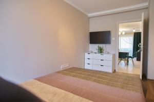a bedroom with a bed with a dresser and a tv at Sunlight Green - Szeged in Szeged