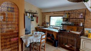 a kitchen with a table and a sink and a table and chairs at L'olivier sur la place in La Rochegiron