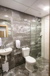 a bathroom with a toilet and a sink and a shower at Хотел Добруджа in Shumen