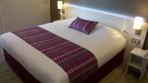 a bed in a hotel room with a pillow on it at Contact Hôtel du Cerf in Château-Gontier
