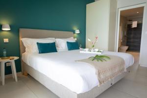a bedroom with a large white bed with blue walls at Eden Roc Villas in Le Diamant