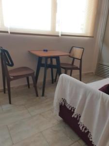 Tiny studio 2 min walking distance from the port في فولوس: غرفة مع طاولة وكراسي وطاولة