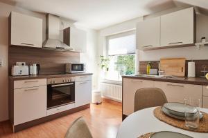 a kitchen with white cabinets and a table with a tableablish at Wohnträumerei - Lichtdurchflutete Design-Oase- Geräumige Wohnung mit beeindruckender Fensterfront, in ruhiger Stadtlage" in Paderborn