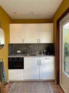 a kitchen with white cabinets and a sink and a window at Bed & Breakfast Danina in Sassenheim