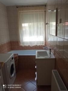 a bathroom with a tub and a sink and a washing machine at Márta Apartman in Hajdúszoboszló