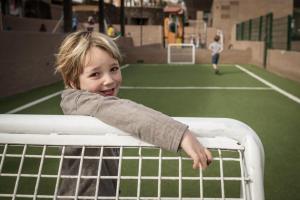 a young boy reaching over the top of a tennis net at Sotavento Beach Club in Costa Calma