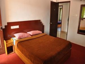 a bedroom with a large bed with a wooden headboard at Hill Heaven Home Stay in Kodaikānāl