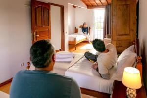2 persone sedute sui letti in una camera d'albergo di Casa de Família ad Angra do Heroísmo