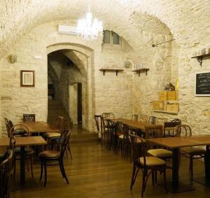 un ristorante con tavoli e sedie in legno e un muro di pietra di Giovinazzo Suite Pavone Griffi a Giovinazzo