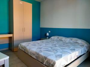 ein Schlafzimmer mit einem Bett, blauen Wänden und einem Schrank in der Unterkunft CARrooms in Carrù