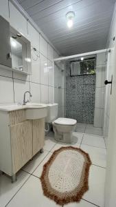 a bathroom with a sink and a toilet and a mirror at Casa das Bromélias- Com Quiosque em meio à natureza! in Piratuba