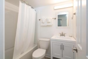 a white bathroom with a toilet and a sink at Lily & Bloom in Myrtle Beach