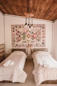 two beds in a room with a painting on the wall at El Rincón. Farm and Lodge in Carmelo