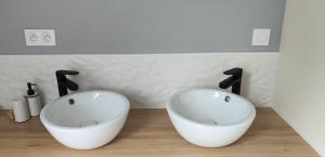 baño con 2 lavabos blancos en una encimera de madera en Les Délices de la Vie, 