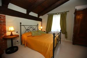 a bedroom with a bed with an orange bedspread and a window at Il Vecchio Mulino Di Bairo in Bairo