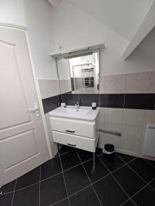 een badkamer met een witte wastafel en een spiegel bij Aux portes de Beauval in Contres
