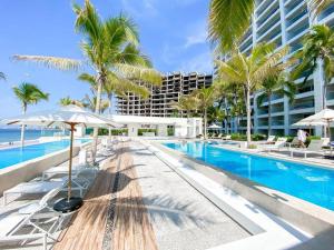 a swimming pool with palm trees and a building at Large Beach Front 2bed/2bath Condo: Save $50+/nt! in Puerto Vallarta
