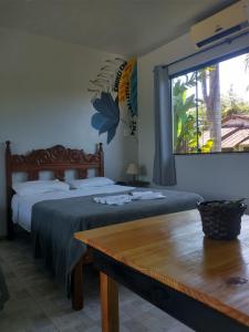 een slaapkamer met 2 bedden, een tafel en een raam bij Pousada Tropicália Paraty in Paraty