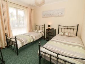 two beds in a room with a window at Willow Lodge in Liskeard
