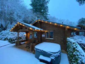 una cabaña cubierta de nieve con luces encendidas en Romantic Log Cabin With Hot Tub, en Leominster
