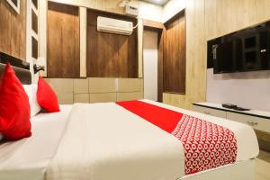 a bedroom with a bed with red pillows and a television at Hotel Sheela in Rohtak