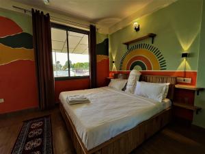 a bedroom with a bed with a rainbow on the wall at THG - The Hidden Garden Bir in Bīr