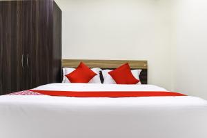 a bed with red and white pillows on it at Flagship S&h Residency in Khandagiri