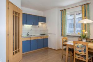 a kitchen with blue cabinets and a dining room table at Valtlhof - Apt 2 in Cornaiano