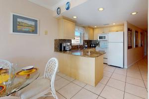 a kitchen with a table and a white refrigerator at 508 - South Beach Condos in St. Pete Beach