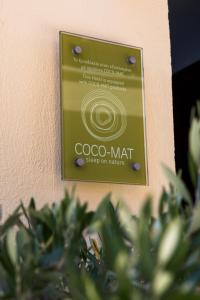 a sign for a coo mat on a wall at Helianthus Guesthouse in Ammouliani