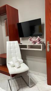 ein Wohnzimmer mit einem weißen Stuhl und einem Flachbild-TV in der Unterkunft PREMIUM SUITES in Ofrynio
