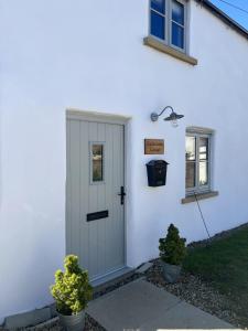 uma casa branca com uma porta e dois vasos de plantas em Blacksmiths Cottages em Filey