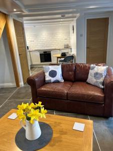 sala de estar con sofá marrón y mesa con flores en Pendragon, en Penzance