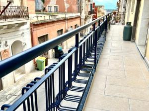 einen Balkon mit blauem Geländer auf einer Stadtstraße in der Unterkunft Bilocale Nel Centro Storico - Prossimo al Mare in Pachino