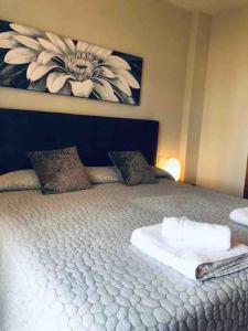 a bedroom with a large bed with a flower painting on the wall at La Manga Club Resort - 3 bedroom Duplex - La Colina in Atamaría