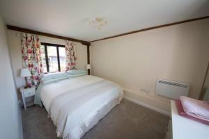 um quarto com uma grande cama branca e uma janela em Rural cottage with swimming pool! em High Halden