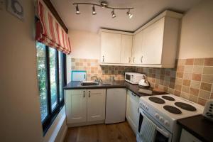 uma cozinha com armários brancos e um forno com placa de fogão em Rural cottage with swimming pool! em High Halden