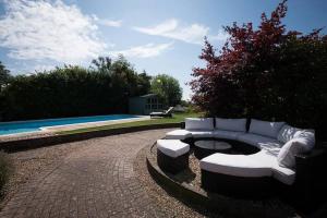 a patio with a white couch andools next to a pool at Rural cottage with swimming pool! in High Halden