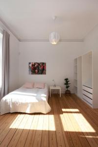 a white bedroom with a bed and a wooden floor at Scandi-Hygge Seaside House - only 10mins to Copenhagen in Charlottenlund