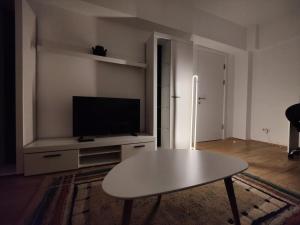 Il comprend un salon doté d'une table et d'une télévision à écran plat. dans l'établissement Apartament The Cozy Nest Turda, à Bucarest